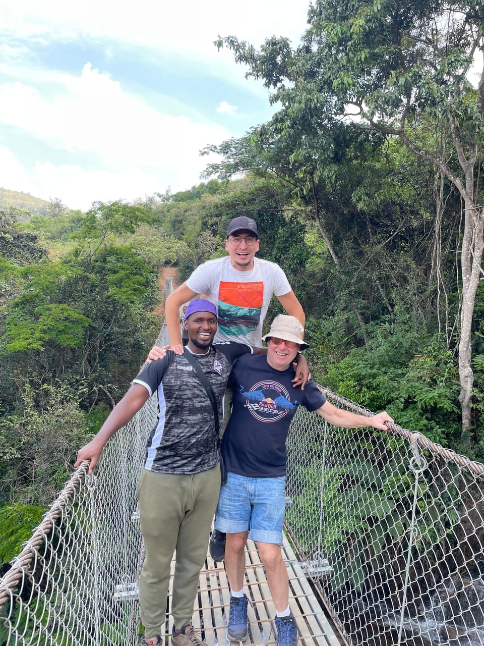 Family crossing a forest suspension bridge with their guide