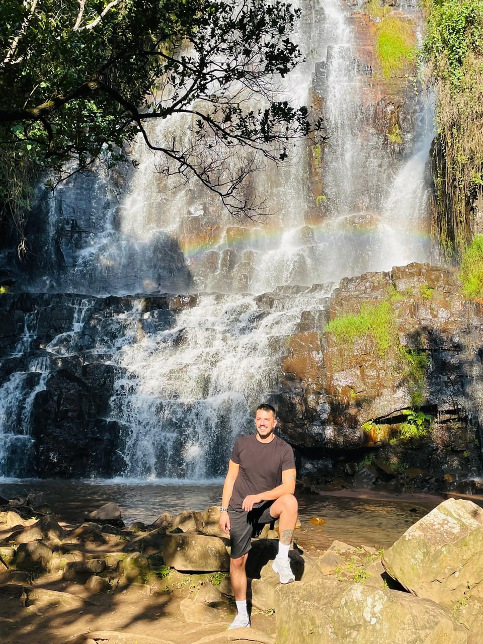 Visitor at a waterfall with a rainbow on a Burundi day trip